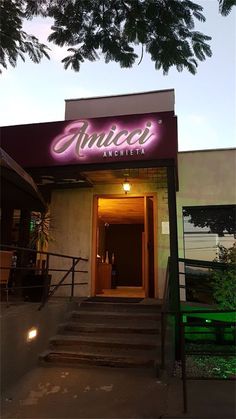 the entrance to an upscale hotel with stairs leading up to it and lit sign above