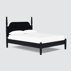 a black bed frame with white sheets and pillows