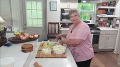 an older woman preparing food in the kitchen on a wooden cutting board next to a counter