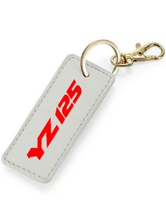 Are you looking for a personalized key ring to treat yourself or to give a gift to a YZ125 enthusiast? This personalized key ring, specially designed for Yamaha YZ 125 enthusiasts, will be perfect! This key ring in synthetic leather-look material is fully customizable and available in 6 colors: blue, white, black, gray, pink or brown. It is particularly intended for owners of YZ 125 from Yamaha. To make it a unique model, you can personalize the color of the text by choosing from 8 colors Key ri White Rectangular Keychain For Gift, White Keychain With Key Clip Gift, White Rectangular Keychain Gift, White Keychain With Key Clip For Gift, White Rectangular Keychains For Gifts, Customizable White Keychains For Personalized Gifts, Rectangular White Keychains, Moto Yamaha, Biker Gifts