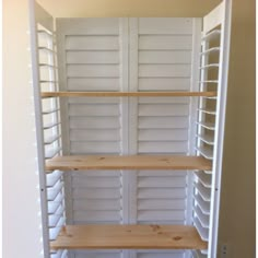 an empty pantry with white shelving and wooden shelves