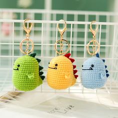 three crocheted keychains hanging on a rack with other items in the background