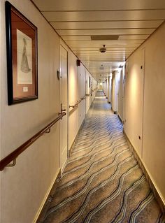 a long hallway with white walls and carpeted flooring