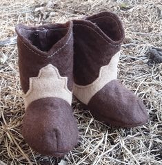 a pair of brown and white boots sitting on top of dry grass