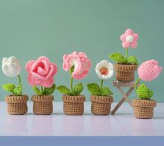 small crocheted flowers in pots on a table