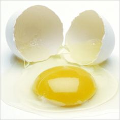 an egg shell with two halves cut in half on a white surface, showing the yolk inside