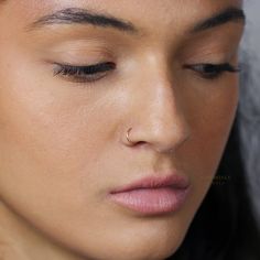 a close up of a woman with her eyes closed and nose piercings in place