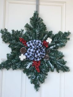 a snowflake wreath hanging on a door with pine cones and berries around it