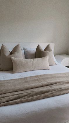 a white bed with four pillows on it