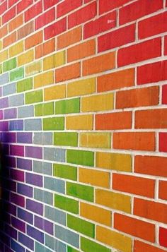 a brick wall painted in rainbow colors with a phone on the ground next to it