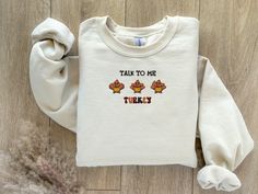 Talk to me turkey is a Funny Thanksgiving embroidered sweatshirt. Wear this warm, cozy, soft, and trendy product on any occasion. Make a statement with this cute turkey embroidery unique design. Also, this design will make a perfect Thanksgiving, fall, birthday, Halloween, and fall festival gift.  Material: * 50% cotton, 50% polyester * Pre-shrunk * Classic fit * 1x1 athletic rib knit collar with spandex * Air-jet spun yarn with a soft feel and reduced pilling * Double-needle stitched collar, sh Fall Fleece Tops With Letter Embroidery, Fleece Sweater With Letter Embroidery For Fall, Fleece Sweatshirt With Letter Embroidery For Fall, Fall Fleece Top With Embroidered Graphics, Fall Fleece Sweatshirt With Embroidered Text, Fall Fleece Sweater With Embroidered Text, Fall Embroidered Text Fleece Sweater, Embroidered Fleece Sweatshirt For Fall, Turkey Embroidery