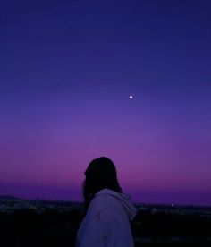 a person standing in front of a purple and blue sky with the moon behind them