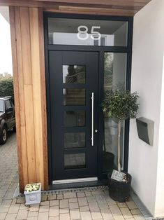 a black front door with glass panels and a potted plant on the side walk