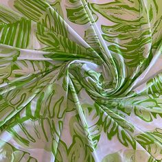 a green and white tropical print fabric with leaves on it's back side, as seen from above