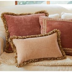 three pillows on a couch with gold sequins and fringe trim around the edges