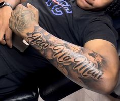 a man with tattoos on his arm sitting in a chair