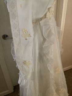 This nice 1970's white beautiful Pinafore dress with sheer sleeve and lace appliqués on it. The dress has a v neck with ruffle. High waist with lace appliqués and then a pinafore ruffle that carries down the front to like a bib at bottom of dress small train. At the very bottom of dress is a stain. Looks like from dragging on ground. Same ruffle design goes around bottom of dress. Chiffon like material on top satin slip underneath . There is also one spot same color as on bottom on side of back White Lace Dresses With Lace Cuffs, Summer Wedding Lace Dress With Lace Cuffs, White Floor-length Lace Dress With Patchwork, White Floor-length Lace Patchwork Dress, White Lace First Communion Dress With Ruffles, Fitted Lace Work First Communion Dress For Wedding, White Lace First Communion Dress For Summer, White Scalloped Lace Floor-length Dress, White Floor-length Lace Dress With Scalloped Lace