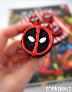 a hand holding a small toy made to look like a deadpool character with eyes