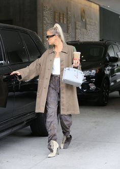 a woman walking down the street with her handbag and ice cream in her hand