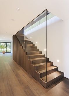 a wooden staircase with glass balustrades in a modern style home, leading up to the second floor