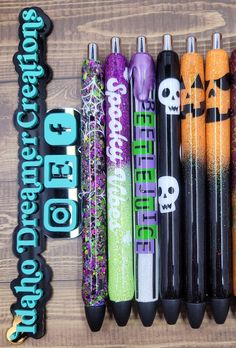 several halloween themed pens lined up on a wooden surface with the words happy halloween written in large letters