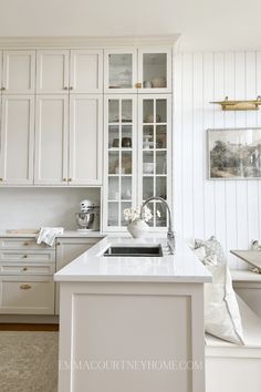 a kitchen with white cabinets and marble counter tops