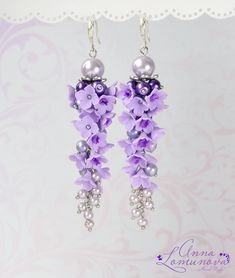 the earrings are decorated with purple flowers and pearls