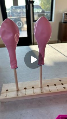 two pink boxing gloves sitting on top of wooden pegs