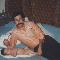 a man holding a baby on top of a bed