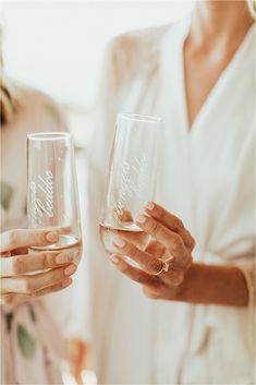 two women are holding wine glasses with the words happily married written on them and one is holding her hand