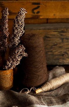 two spools of brown yarn next to each other on a wooden tablecloth