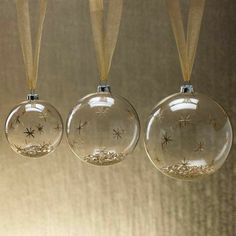 three glass ornaments hanging from a ceiling with gold ribbon and starburst designs on them