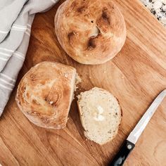 two loaves of bread sitting on top of a cutting board next to a knife