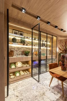 a wooden table sitting inside of a room next to shelves filled with dishes and vases