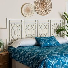 a bed with blue sheets and pillows in a bedroom next to two plants on the wall