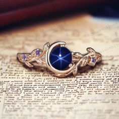 a blue stone ring sitting on top of an open book