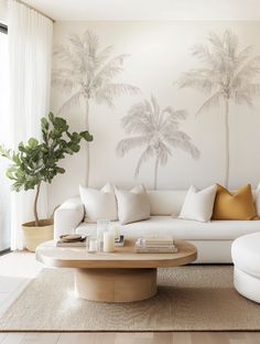 a living room with palm trees painted on the wall and white couches in front