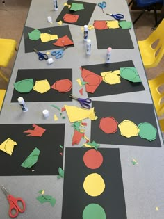 the table is covered with construction paper cutouts, scissors and glue on top of them