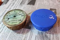 a blue stopwatch sitting on top of a newspaper with the word tops written on it