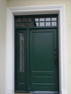 a green front door with two sidelights on the top and bottom, next to a white wall