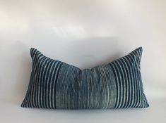 a black and white striped pillow sitting on top of a white table next to a wall