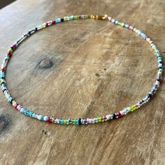 a multicolored beaded necklace sitting on top of a wooden table