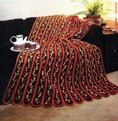 a blanket is draped over a couch with a coffee cup and pot on the table