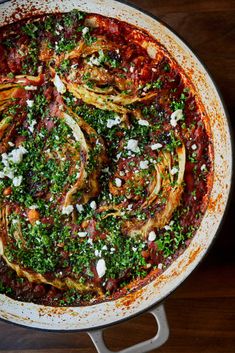 a pan filled with vegetables and sauce on top of a wooden table