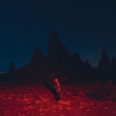 a man standing on top of a rocky field under a night sky