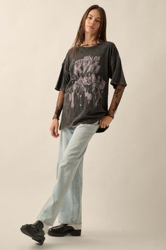 a woman standing in front of a white background wearing jeans and a black t - shirt