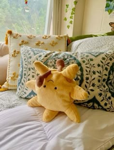 a yellow stuffed animal laying on top of a white bed next to pillows and pillow cases