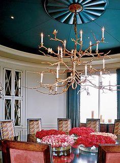 a dining room table with chairs and a chandelier hanging from the ceiling above it