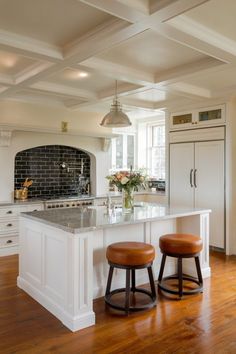 two stools sit at the center of a kitchen island in front of an oven