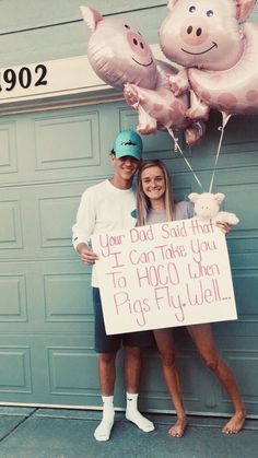 a man and woman standing next to each other with balloons in the shape of pigs